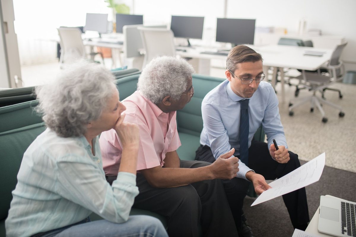 Financial advisor in an office explaining a printed retirement plan document to a senior couple