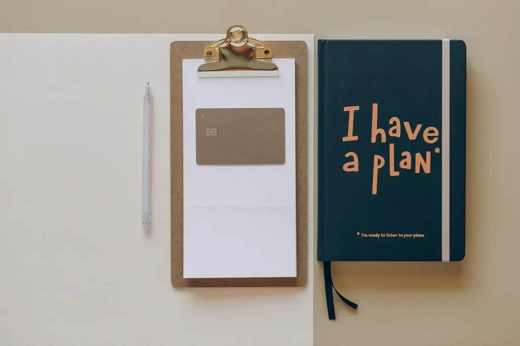 Clipboard with a card and a notebook reading I have a plan, a step-by-step plan to improve your credit score