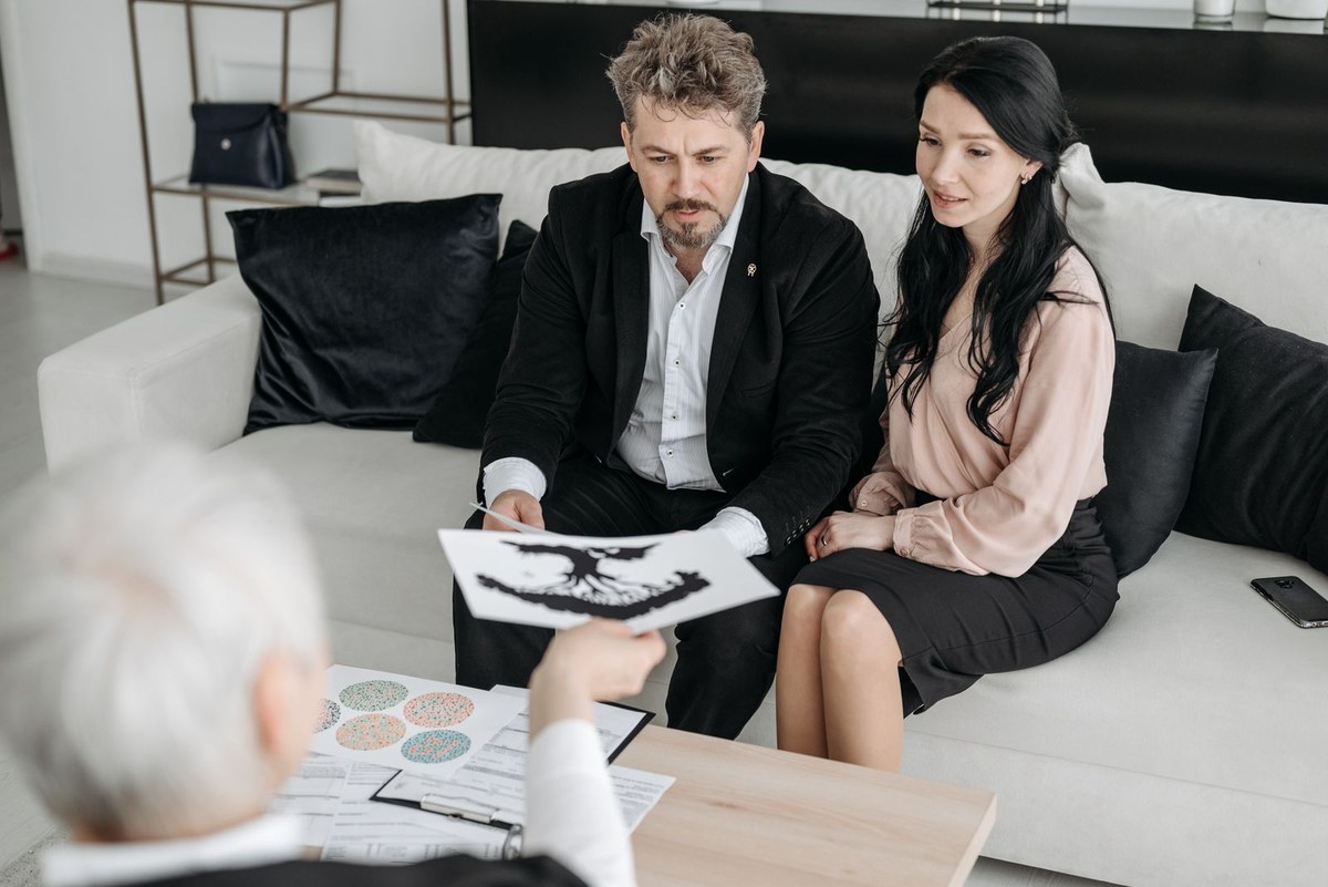 Couple sitting on a sofa reviewing documents with a professional advisor in a home office