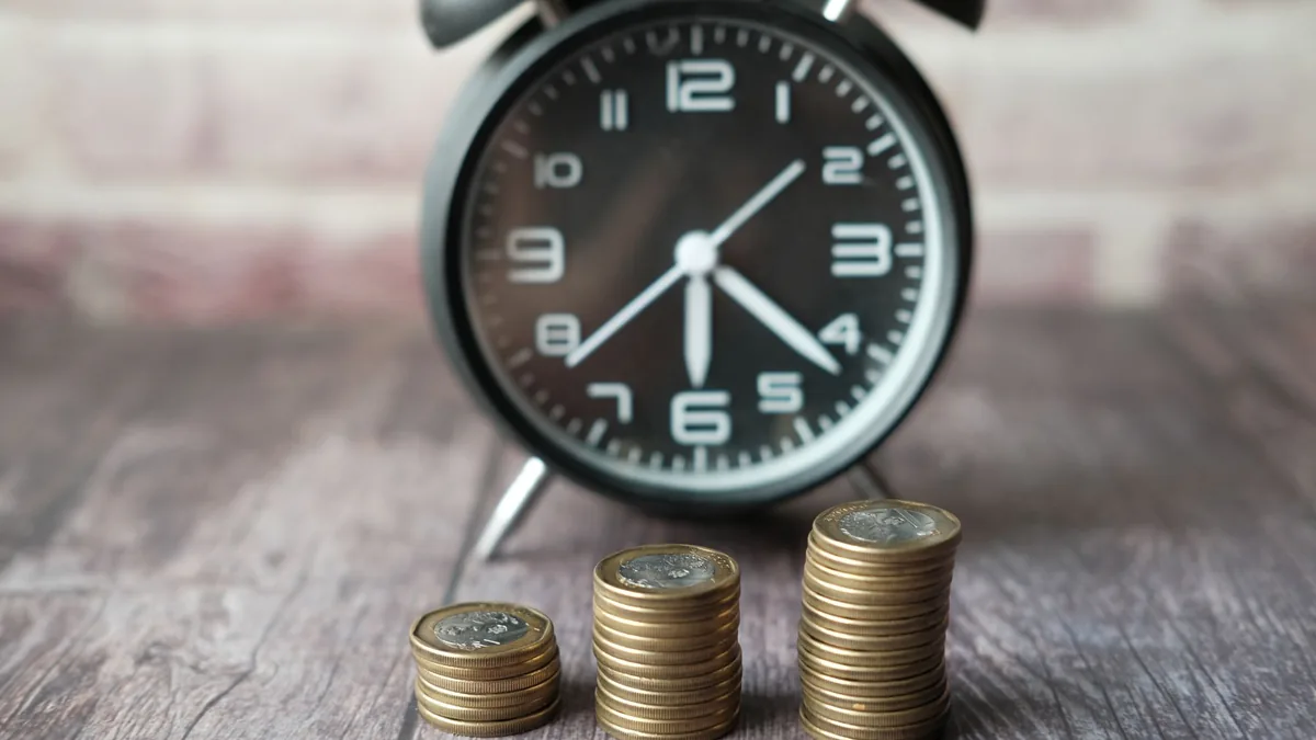 Stacks of coins and an alarm clock symbolizing Roth IRA vs. traditional IRA retirement savings over time